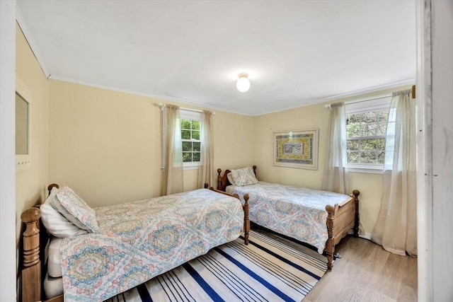 bedroom with wood finished floors and crown molding