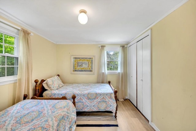 bedroom with light wood-style flooring, ornamental molding, and a closet