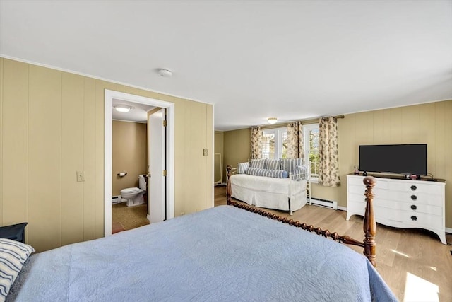 bedroom with a baseboard radiator, wood finished floors, and ensuite bathroom