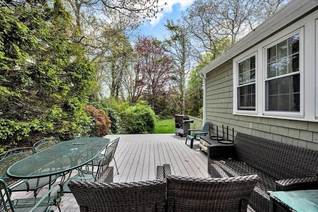 wooden terrace featuring outdoor dining area and view of wooded area