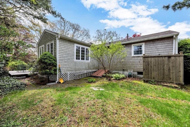 back of property featuring a wooden deck and a lawn