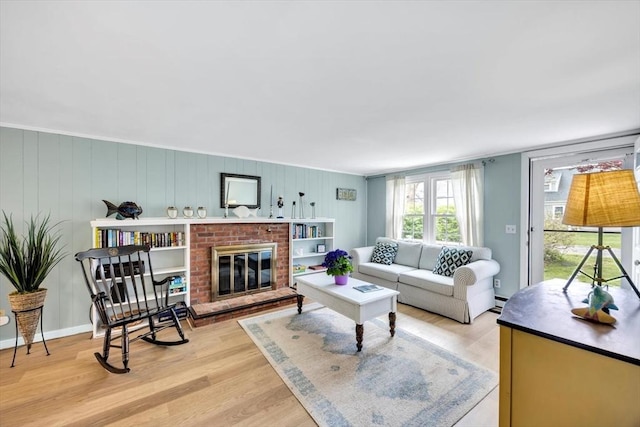 living area with a brick fireplace, wood finished floors, and a baseboard heating unit