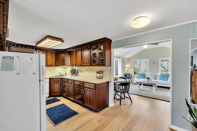 kitchen featuring freestanding refrigerator, light wood-type flooring, light countertops, a sink, and ornamental molding