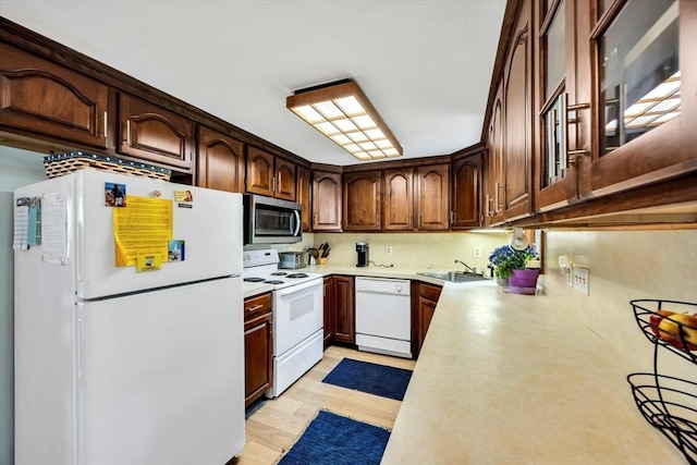 kitchen featuring white appliances, light countertops, light wood-style flooring, a sink, and backsplash