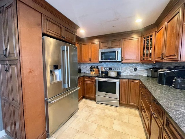 kitchen featuring light tile patterned floors, stainless steel appliances, decorative backsplash, and dark stone counters