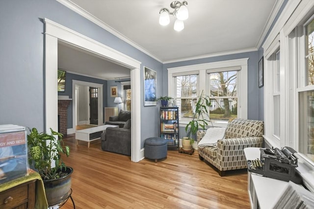 sitting room featuring a fireplace, crown molding, and wood finished floors