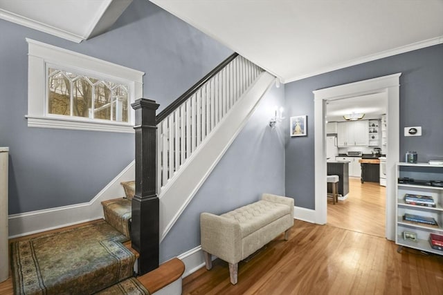 stairs featuring ornamental molding, baseboards, and wood finished floors