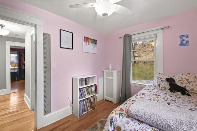 bedroom with a ceiling fan, multiple windows, baseboards, and light wood-type flooring