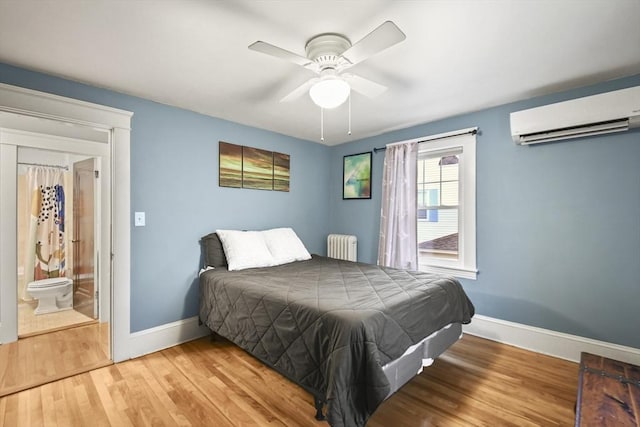 bedroom with a ceiling fan, wood finished floors, radiator heating unit, a wall unit AC, and baseboards