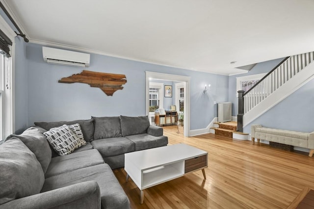 living area featuring crown molding, baseboards, stairway, an AC wall unit, and wood finished floors