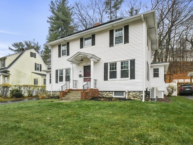 colonial-style house with a front lawn, central air condition unit, and a chimney