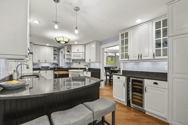 kitchen featuring a sink, white cabinetry, wine cooler, white appliances, and a peninsula