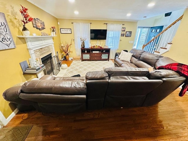 living room with a stone fireplace and wood-type flooring