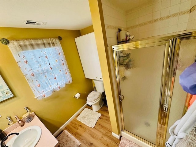 bathroom featuring hardwood / wood-style floors, vanity, toilet, and a shower with shower door