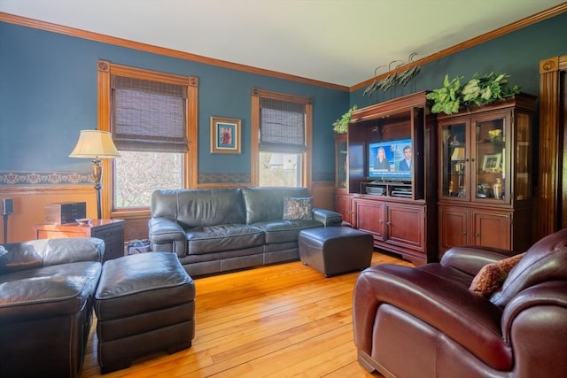 living area featuring wainscoting, ornamental molding, and light wood finished floors