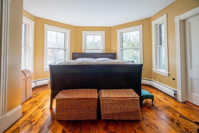 bedroom featuring baseboards, hardwood / wood-style flooring, and a baseboard radiator