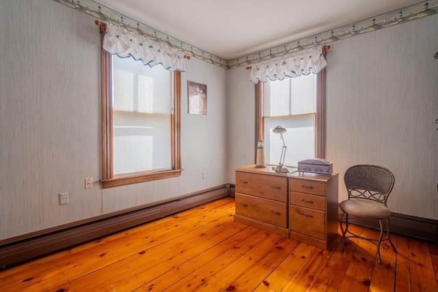 living area with light wood-style floors, baseboard heating, and wallpapered walls