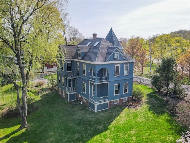 exterior space with a yard, fence, a chimney, and a balcony