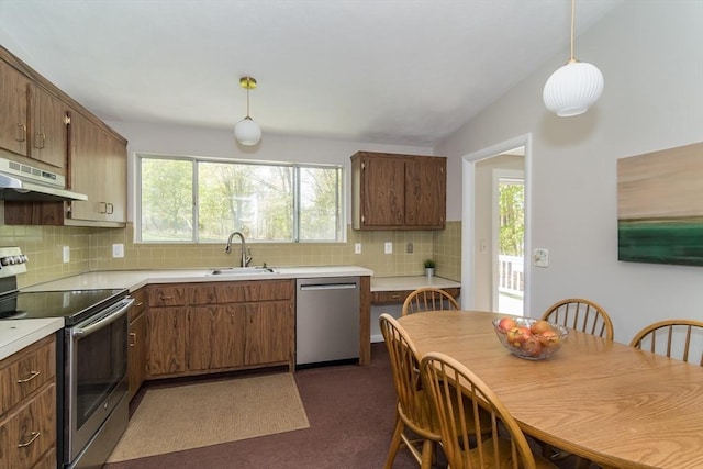kitchen featuring appliances with stainless steel finishes, a sink, light countertops, backsplash, and under cabinet range hood