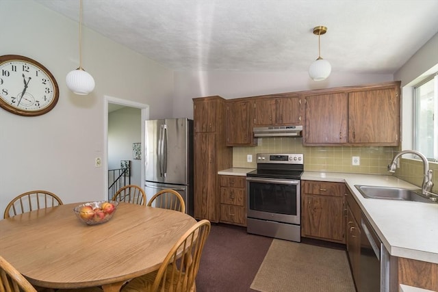 kitchen featuring a sink, light countertops, stainless steel appliances, lofted ceiling, and under cabinet range hood