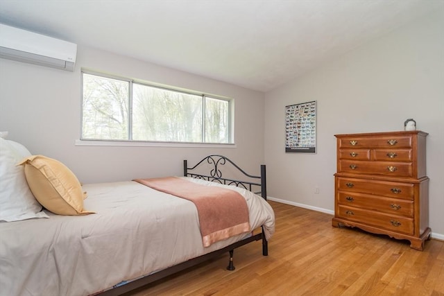 bedroom with light wood-type flooring, a wall mounted air conditioner, and multiple windows