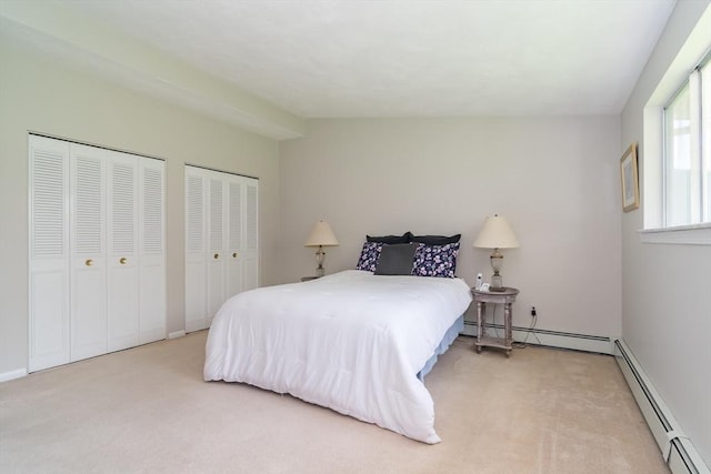 bedroom with carpet floors, a baseboard radiator, baseboards, and two closets