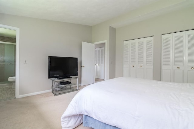 carpeted bedroom with baseboards, connected bathroom, and two closets