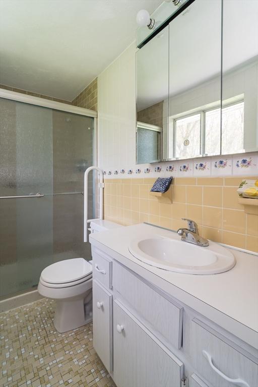 full bathroom with vanity, tile patterned flooring, toilet, tile walls, and a stall shower