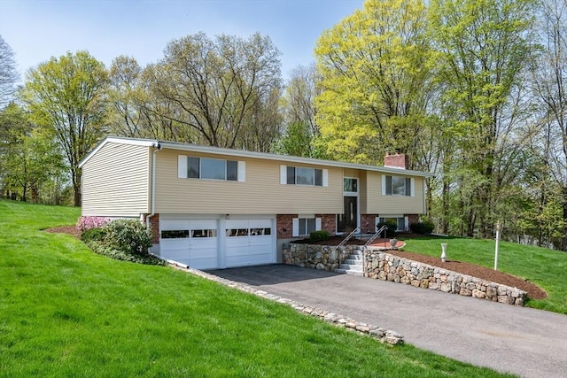raised ranch featuring a garage, a front lawn, aphalt driveway, and a chimney