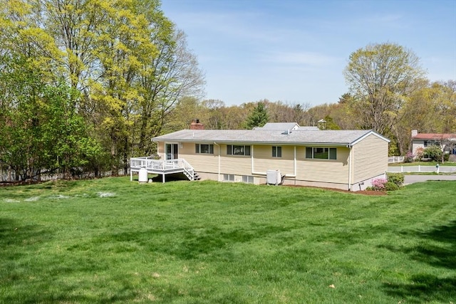 back of property featuring a wooden deck, a chimney, and a yard