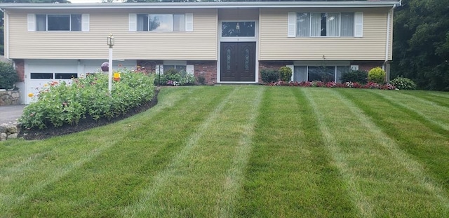 rear view of house featuring a lawn, brick siding, and a garage