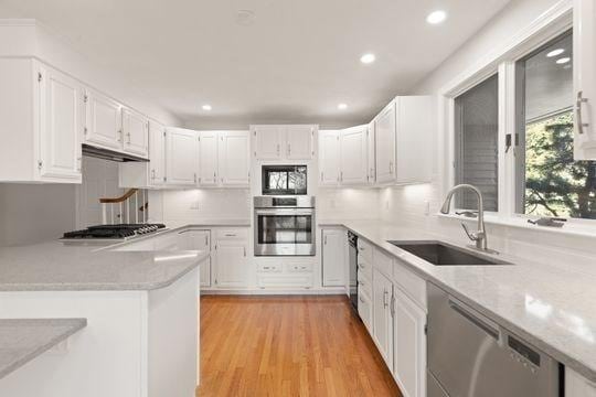 kitchen with stainless steel appliances, a sink, white cabinets, light countertops, and recessed lighting