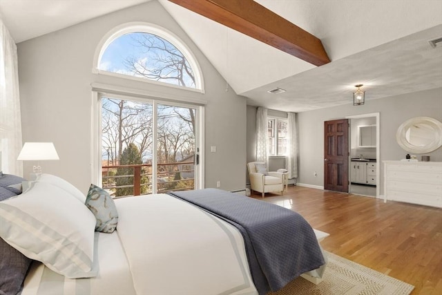 bedroom featuring wood finished floors, high vaulted ceiling, a baseboard heating unit, and connected bathroom
