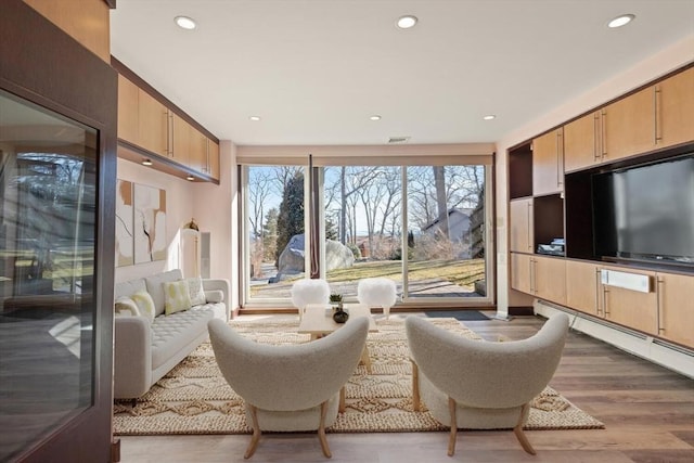 living room with a baseboard heating unit, recessed lighting, and wood finished floors