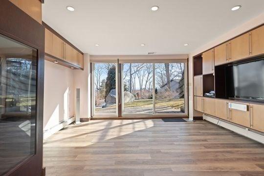 unfurnished living room with wood finished floors, baseboard heating, recessed lighting, and baseboards