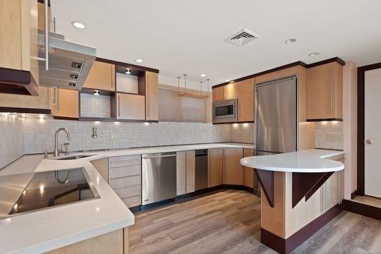 kitchen with appliances with stainless steel finishes, a sink, light wood finished floors, extractor fan, and light countertops