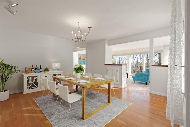dining room with a chandelier, light wood-type flooring, and baseboards