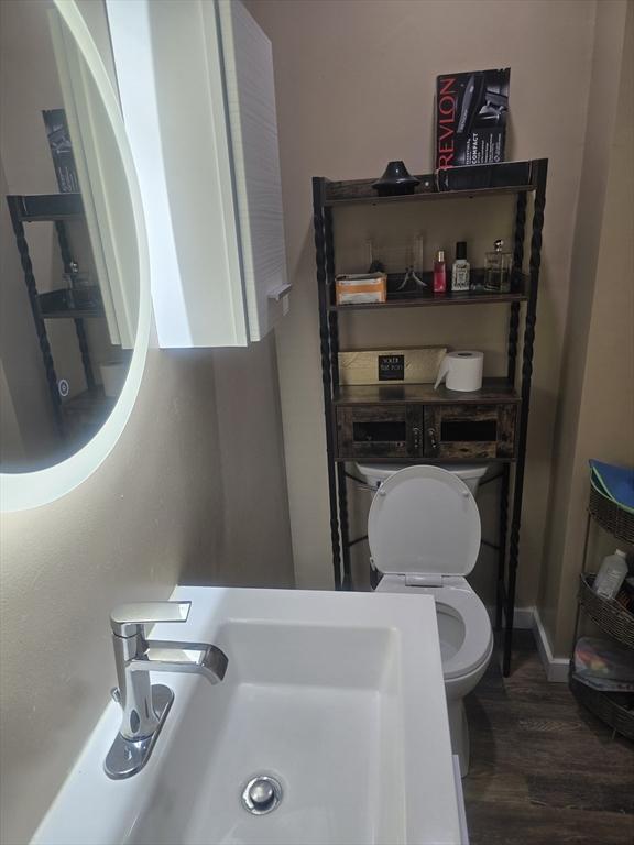 bathroom featuring wood-type flooring, toilet, and sink