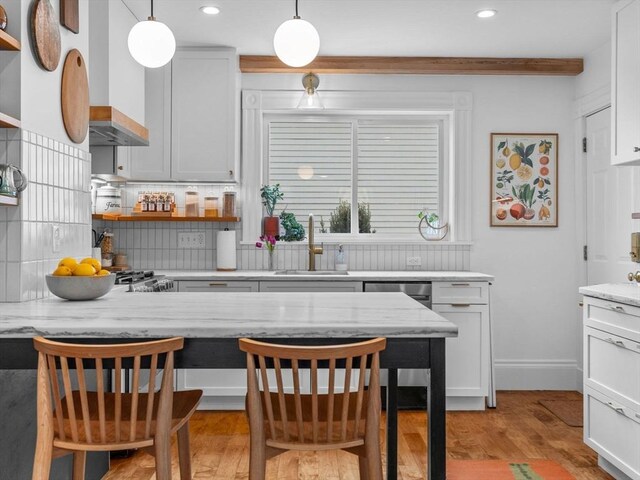 kitchen featuring tasteful backsplash, a sink, open shelves, decorative light fixtures, and light wood-type flooring