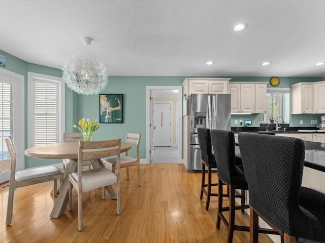 dining area featuring light wood finished floors, a chandelier, recessed lighting, and baseboards