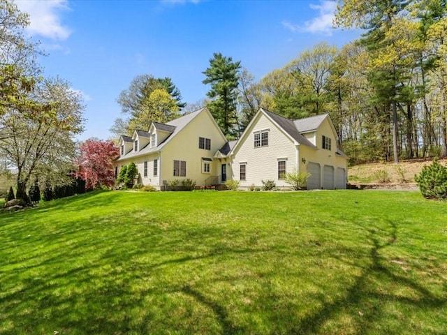 rear view of property with an attached garage and a lawn