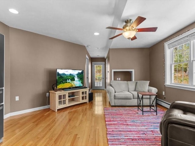 living area with light wood-style flooring, a baseboard heating unit, recessed lighting, a ceiling fan, and baseboards