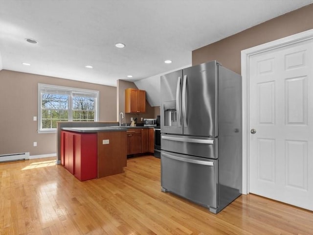 kitchen with stainless steel appliances, a peninsula, light wood-style floors, a sink, and a baseboard heating unit