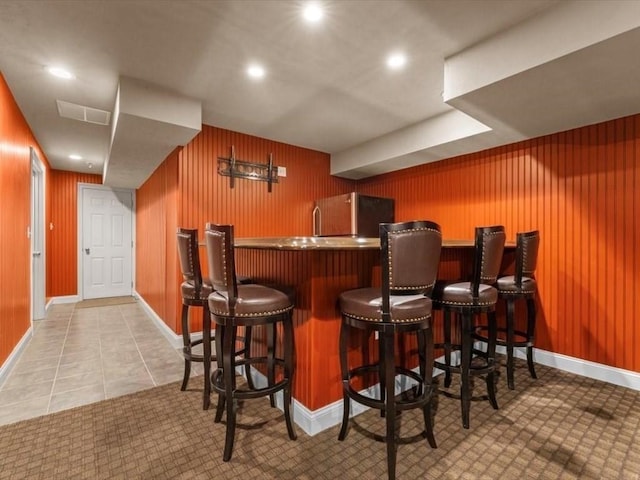 indoor wet bar featuring refrigerator, baseboards, wooden walls, recessed lighting, and tile patterned flooring