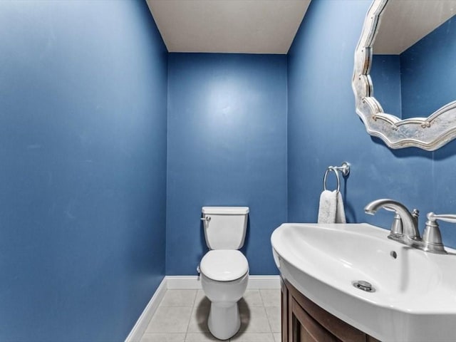 half bath with tile patterned flooring, toilet, baseboards, and vanity