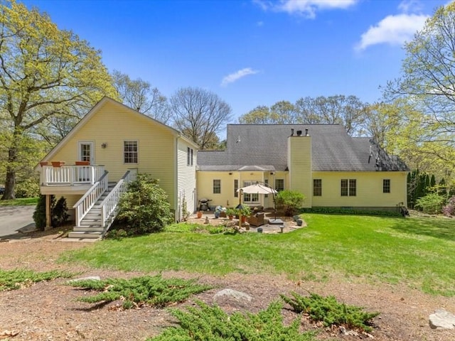 back of house featuring a lawn, stairs, a patio, and a chimney