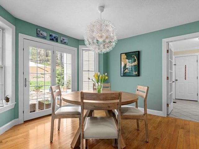 dining room featuring a chandelier, baseboards, and light wood finished floors