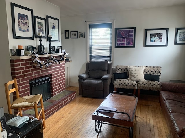 living room featuring wood-type flooring and a brick fireplace