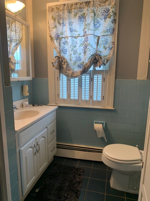 bathroom with tile walls, a baseboard heating unit, vanity, and toilet