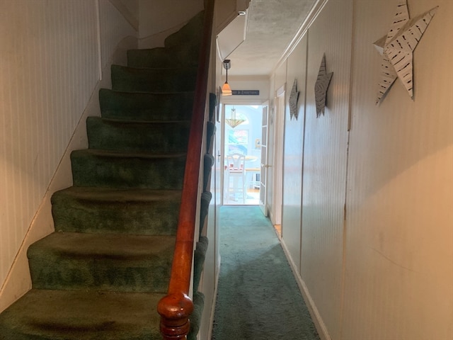 staircase featuring ornamental molding, wood walls, and carpet flooring